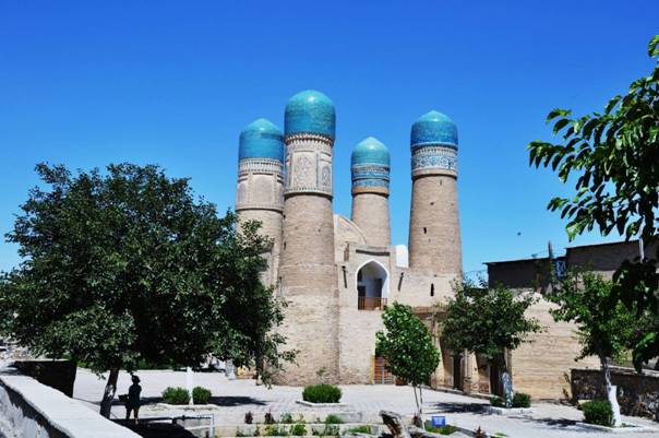 Historisches Gebäude in Usbekistan mit vier blau gekrönten Türmen.