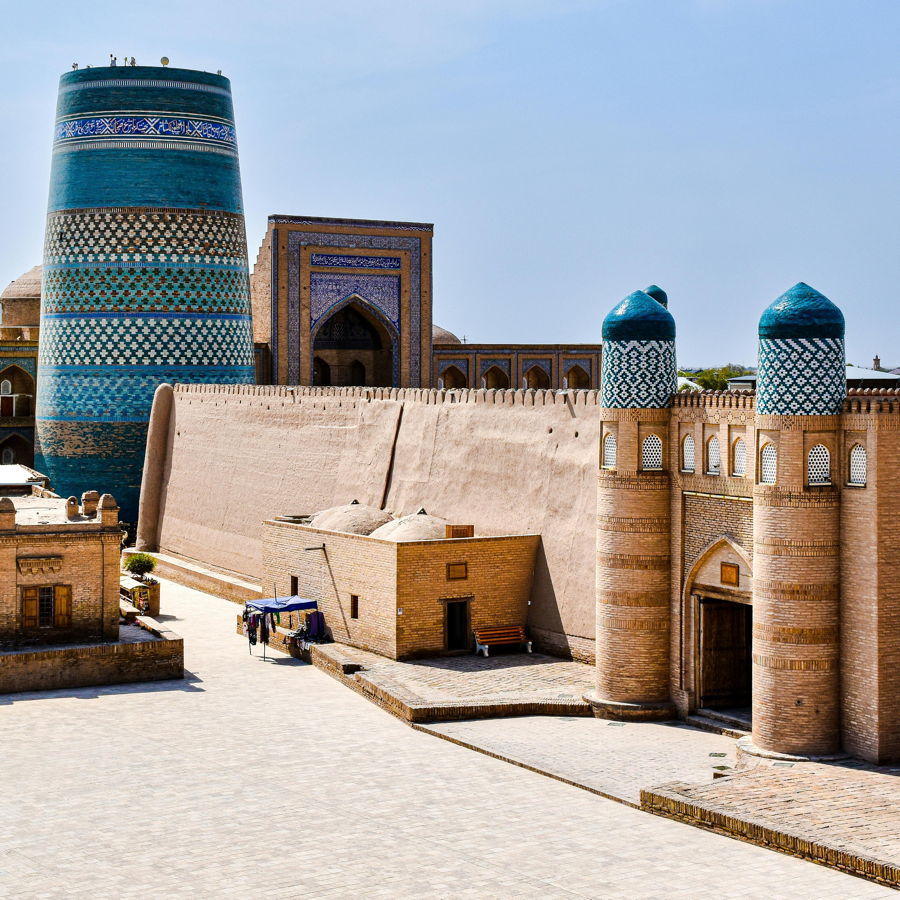 Historische Stadtmauer und blau gefliester Kalta-Minarett-Komplex in Chiwa, Usbekistan, mit auffälligen Musterkacheln und Torbogen