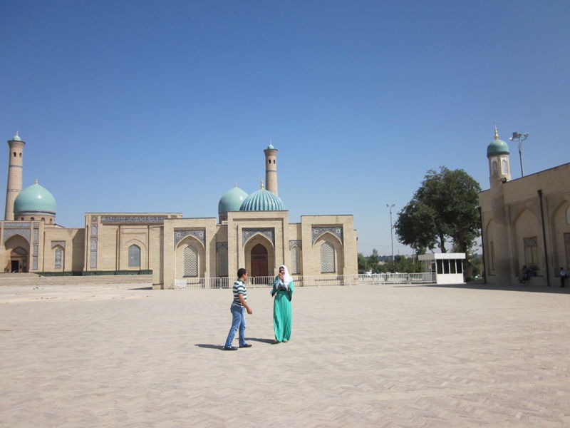 Reise nach Usbekistan 5. September — 16. September 2013 Großer Innenhof einer zentralasiatischen Moschee mit türkisfarbenen Kuppeln, Minaretten und zwei Personen im Vordergrund
